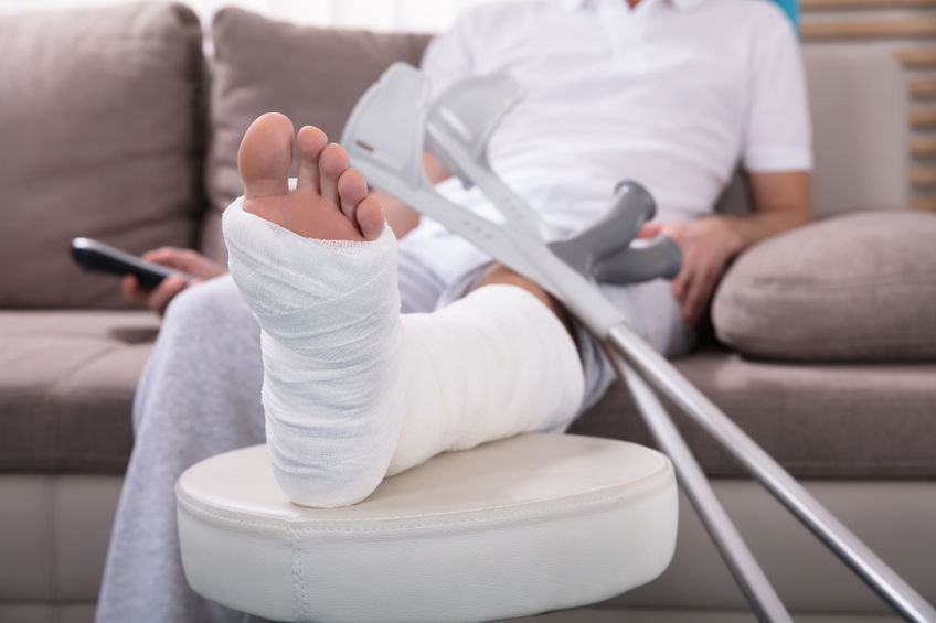 Fotografía que muestra un hombre escayolado, sentado en el sofá, tras sufrir una fractura en la pierna