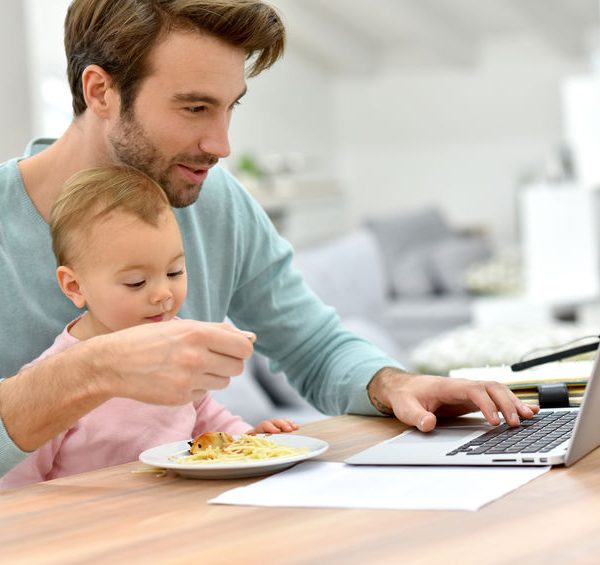 Hombre teletrabajando y atendiendo a su hijo